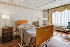 Single occupancy room with bed, wood floors and very large window