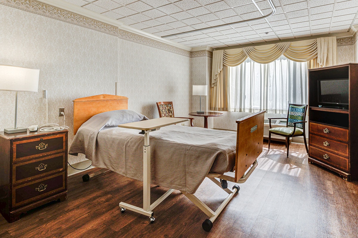 Single occupancy room with bed, wood floors and very large window