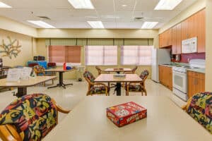 Activity room with tables and chairs, kitchennette, and games like Yahtzee on the tables