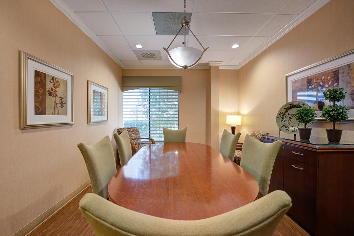 Conference room with large dining room table, buffet and yellow walls.
