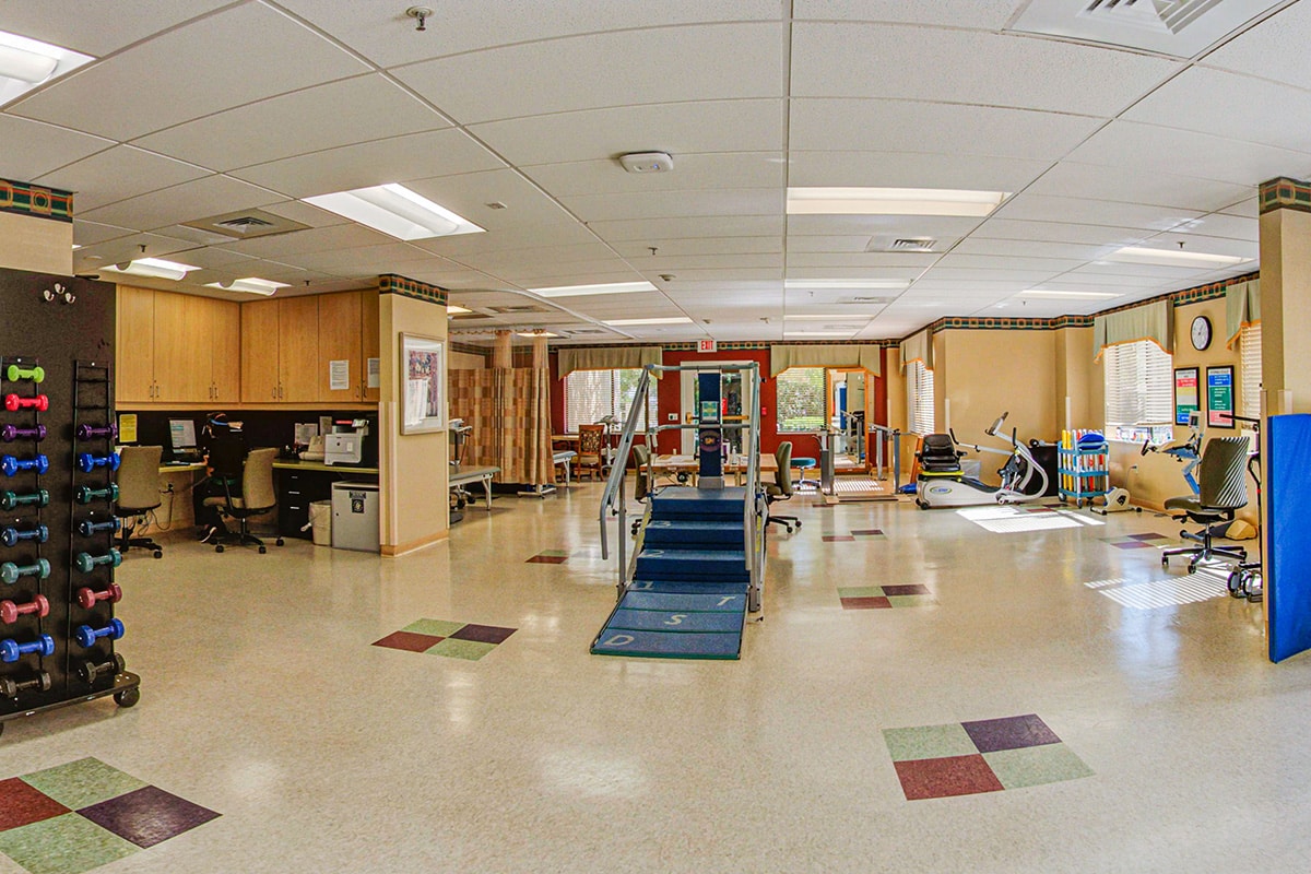 Rehab gym with colorful hand weights and other physical therapy equipment