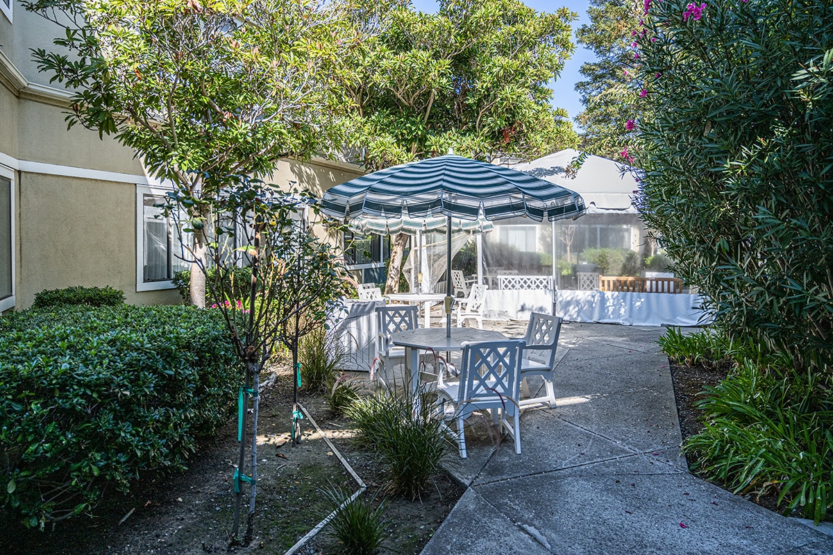 Outside courtyard with table, chairs and striped umbrella